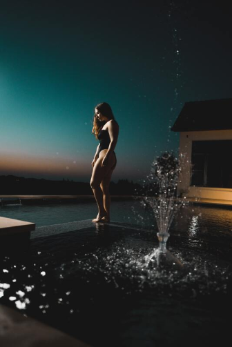 Nighttime view of gorgeous woman standing by pool in Wilmington 